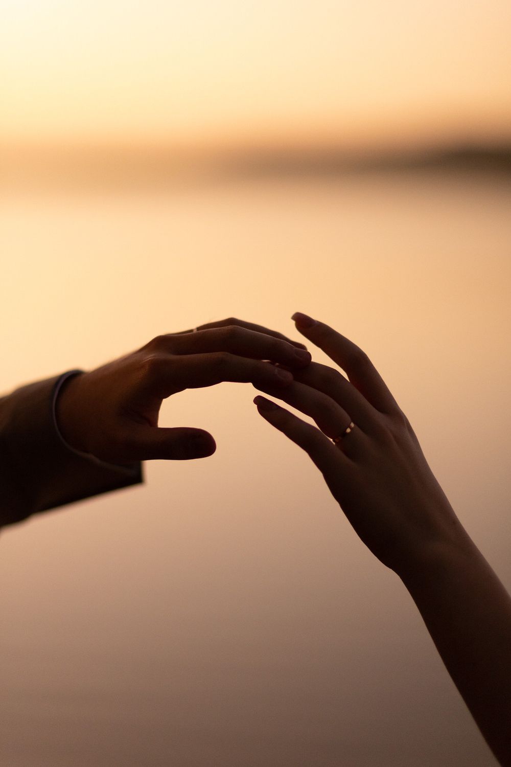 Silhouetted hands in a sequence showing graceful finger movements against a warm sunset background.