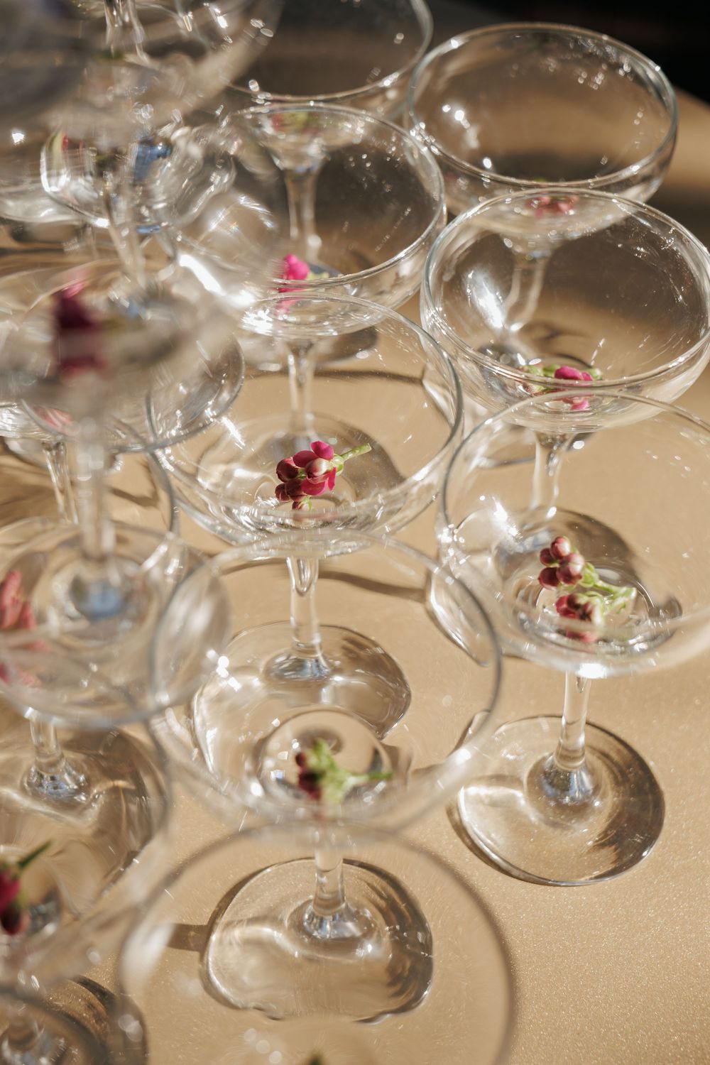 Elegant cocktail glasses arranged in rows with delicate floral garnishes.
