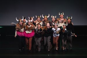 Group performance with dancers wearing viking-style horned headpieces on stage.