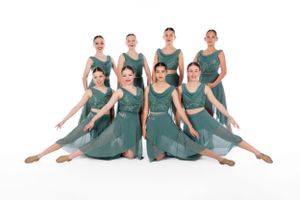 Dance troupe in matching teal dresses performs elegant synchronized routine.