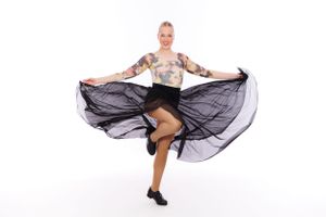 Dancer twirls in flowing black skirt against white background.