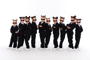 Young dancers in matching black costumes and mouse ears pose in formation.