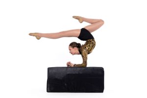 Gymnast performing handstand split on black platform showing flexibility.