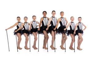 Dance troupe in matching black and white costumes posing in theatrical formation.
