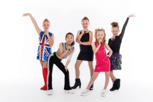 Dance group posing in colorful costumes against white background with Union Jack design.
