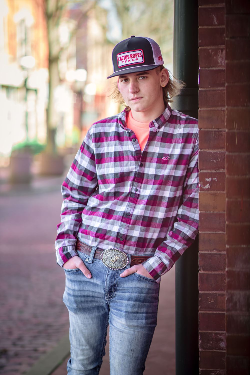 Street style portrait in plaid shirt and branded baseball cap.