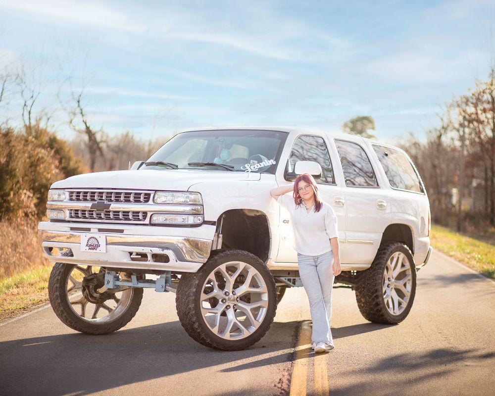 Custom lifted white Chevrolet Tahoe with large wheels photographed on a sunny day.
