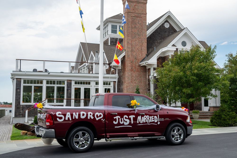 Red truck decorated with Just Married sign parked outside Peconic Bay Yacht Club after wedding.