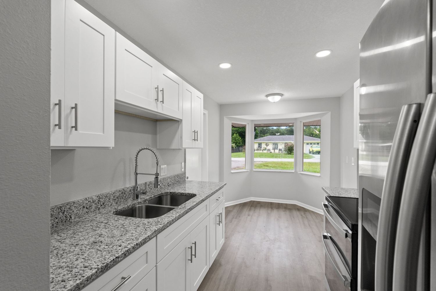 Simple and clean modern kitchen with marble countertops and stainless steel appliances.