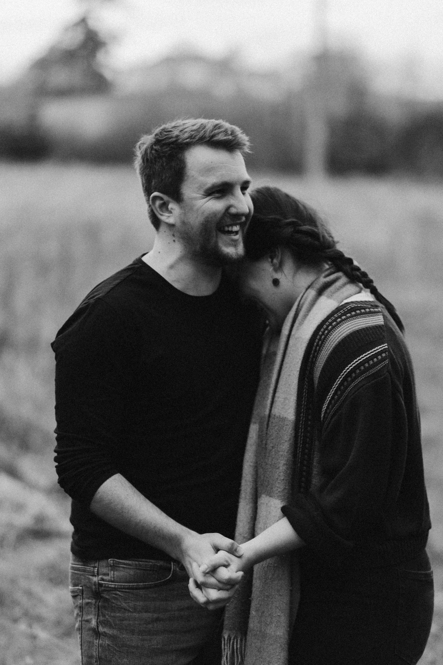 A couple shares a tender moment while holding hands in a black and white portrait.