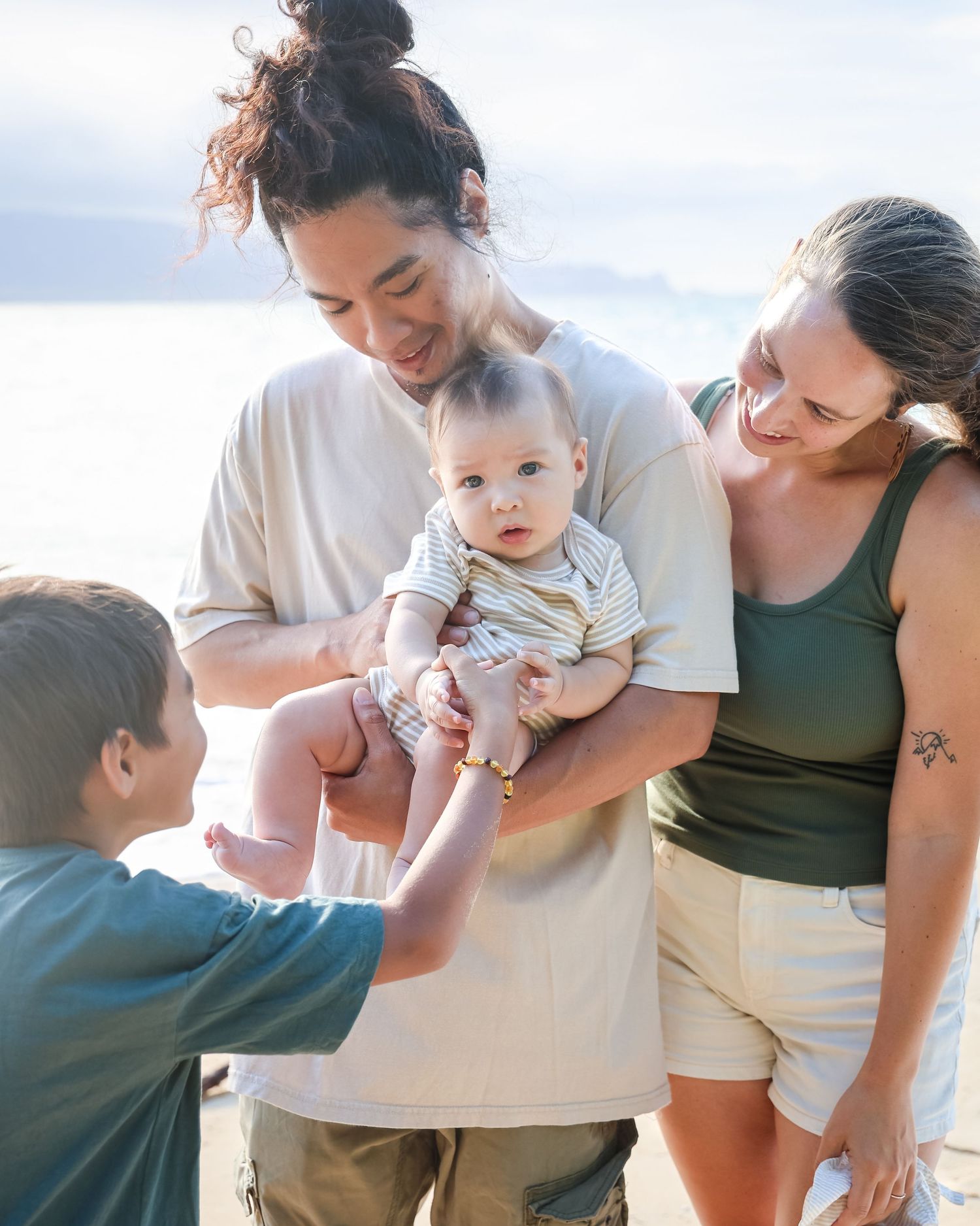 Family walking along a scenic beach at sunset with crashing waves and black volcanic rocks in Hawaii.