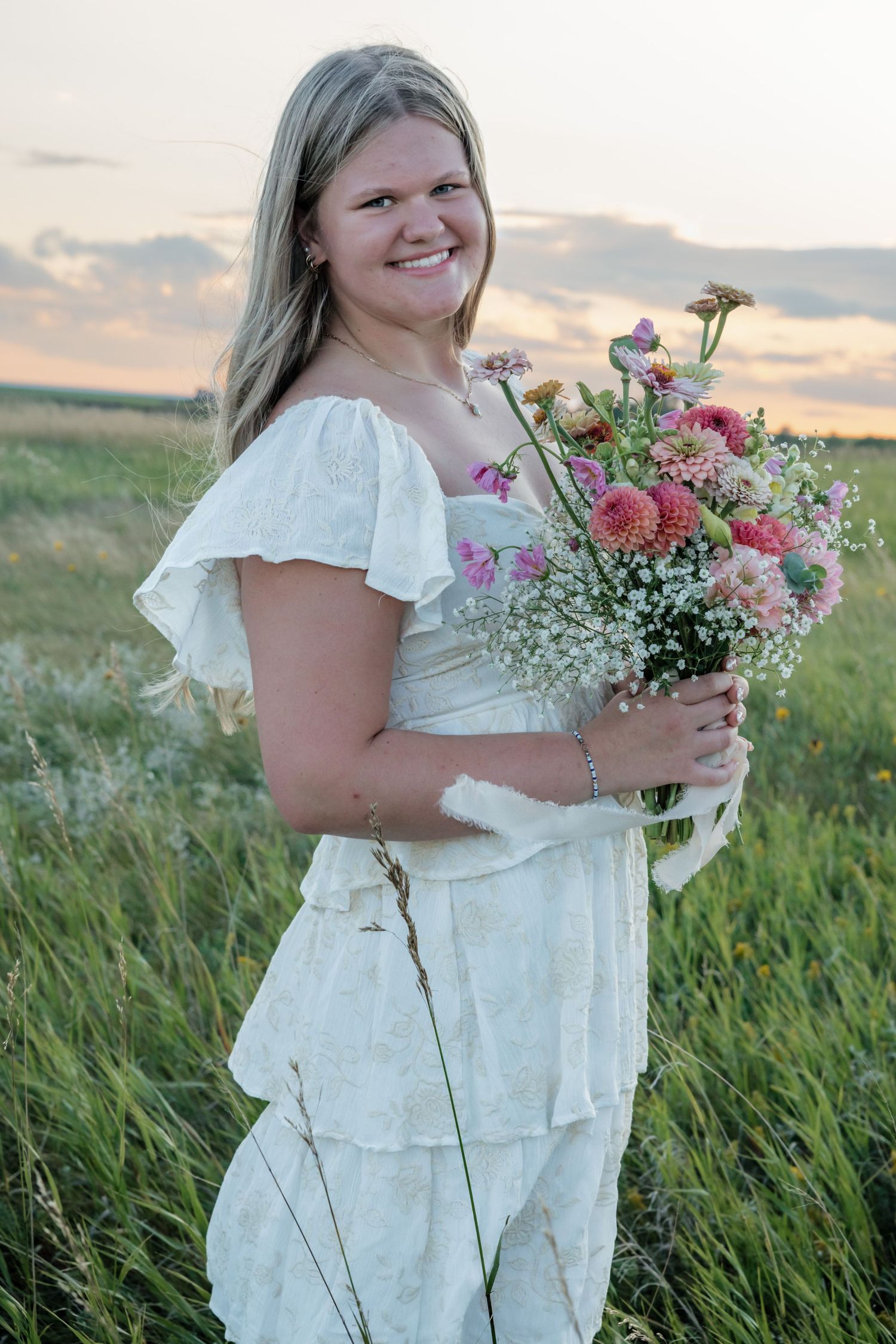 Golden hour senior photos in Bismarck ND featuring student with floral bouquet from Mini Blooms by Emil in outdoor session