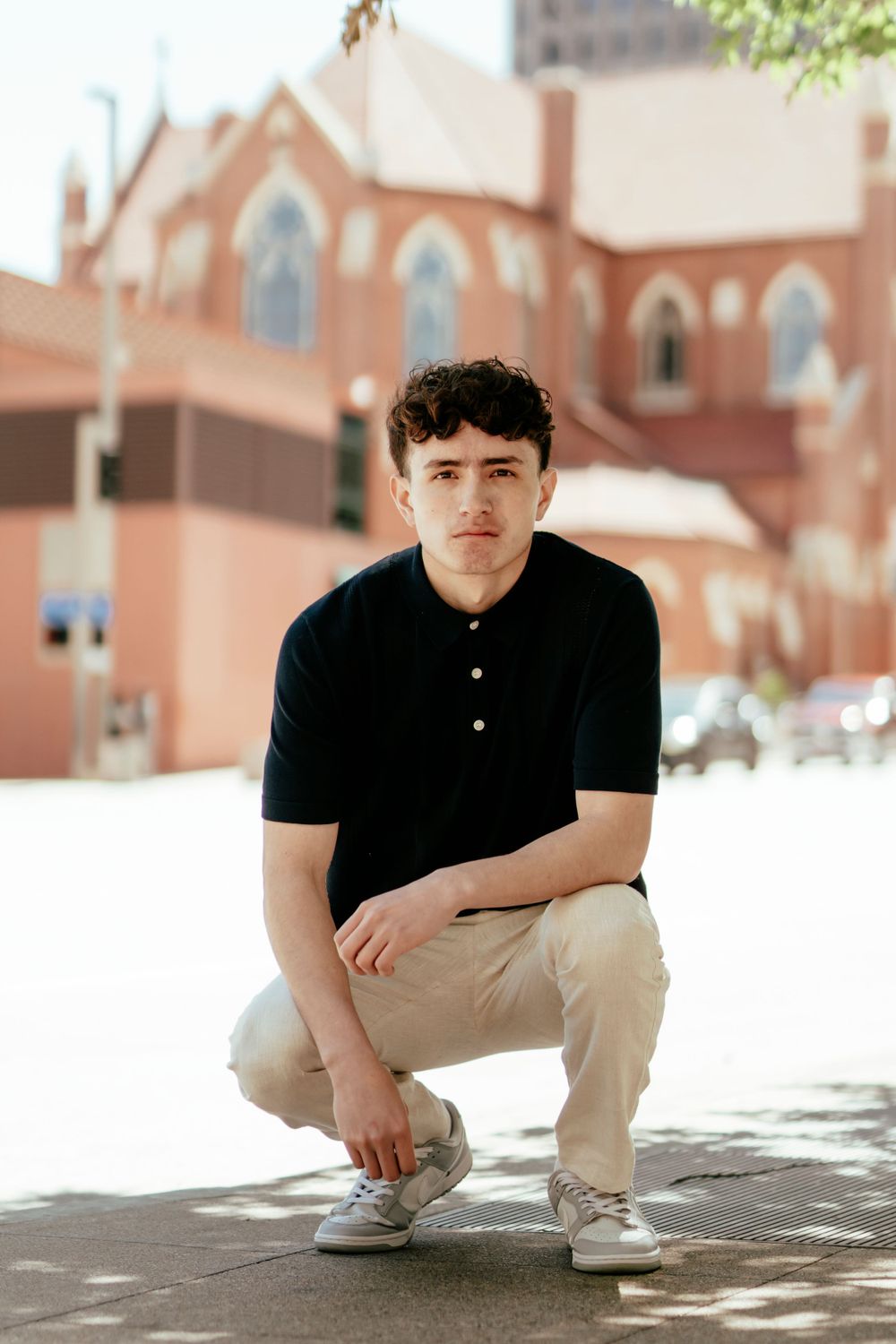 Casual outdoor portrait with red brick church facade visible in background.