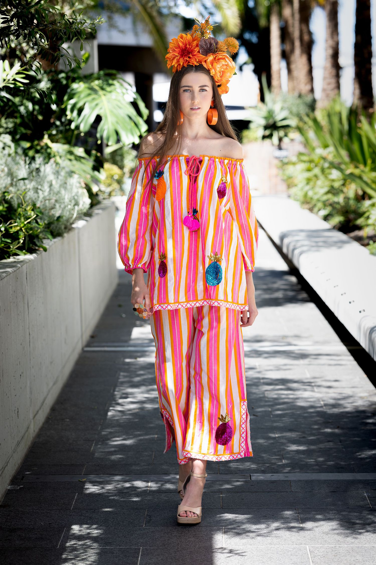 A colorful striped dress is showcased in a series of outdoor photos along a sunlit garden pathway.