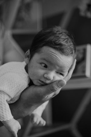 Black and white photo of baby making expressive face while being held.