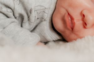 Close-up detail of sleeping newborn swaddled in patterned fabric.