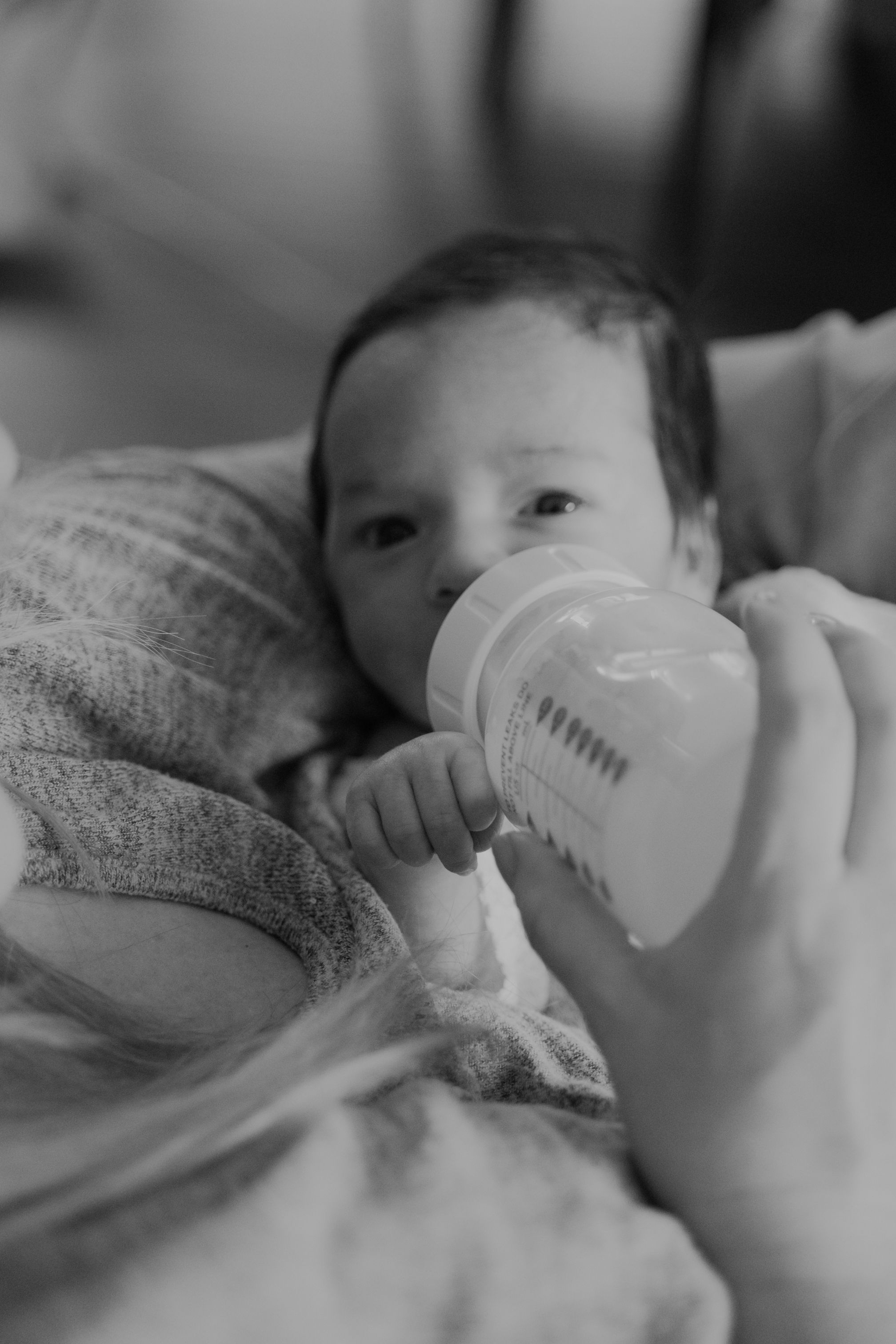 Baby drinking from a bottle in black and white photography.
