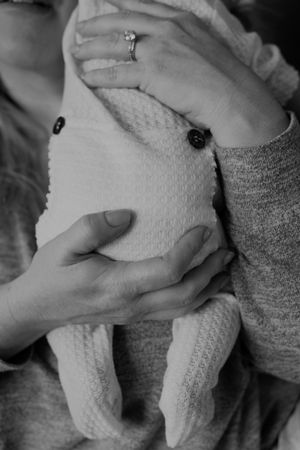 Black and white close-up of hands holding a newborn baby.