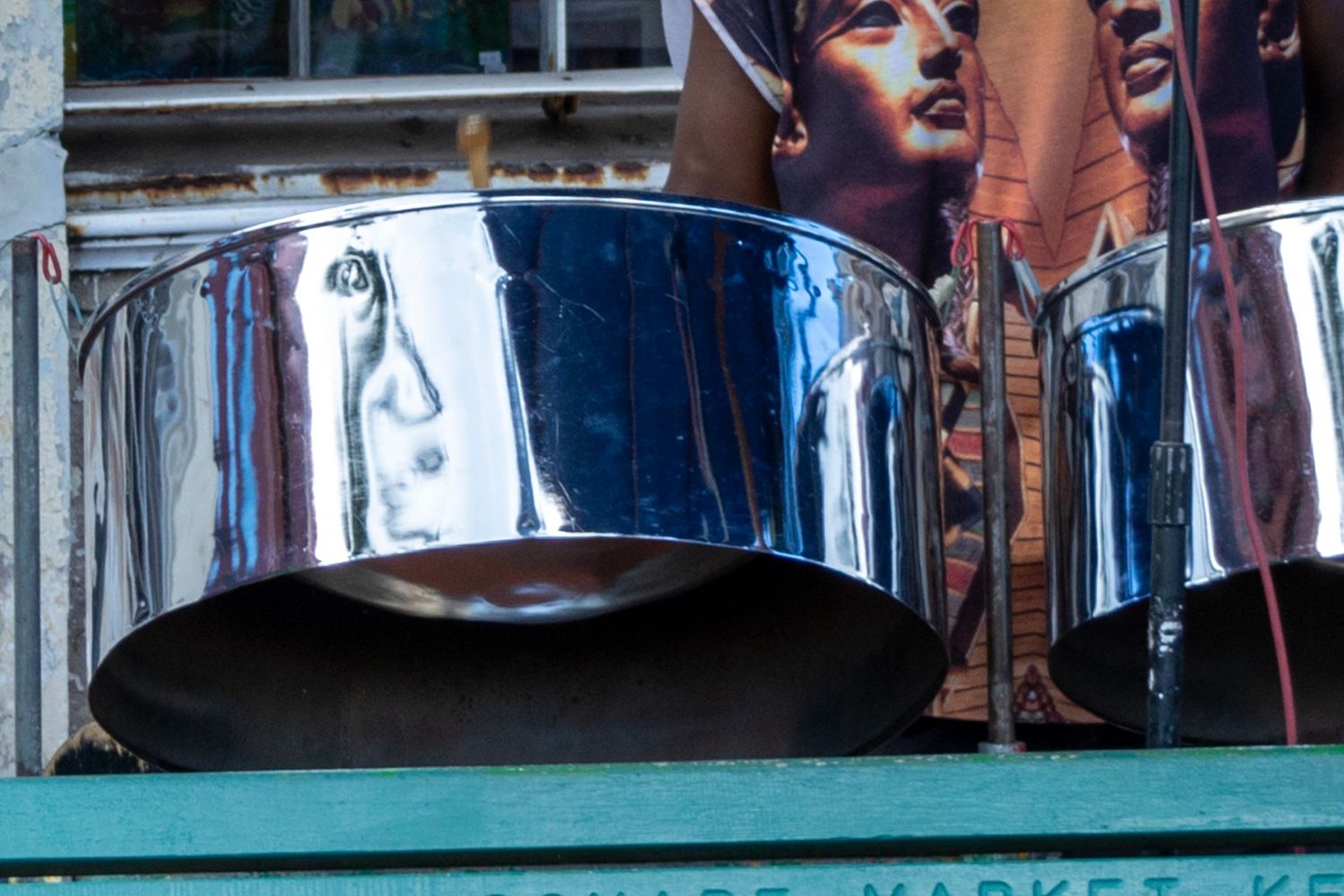 Shiny steel drums on display at an outdoor musical setup.