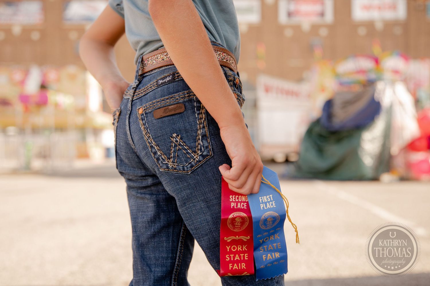 Close-up of prize ribbons in the back pocket of blue jeans at a county fair.