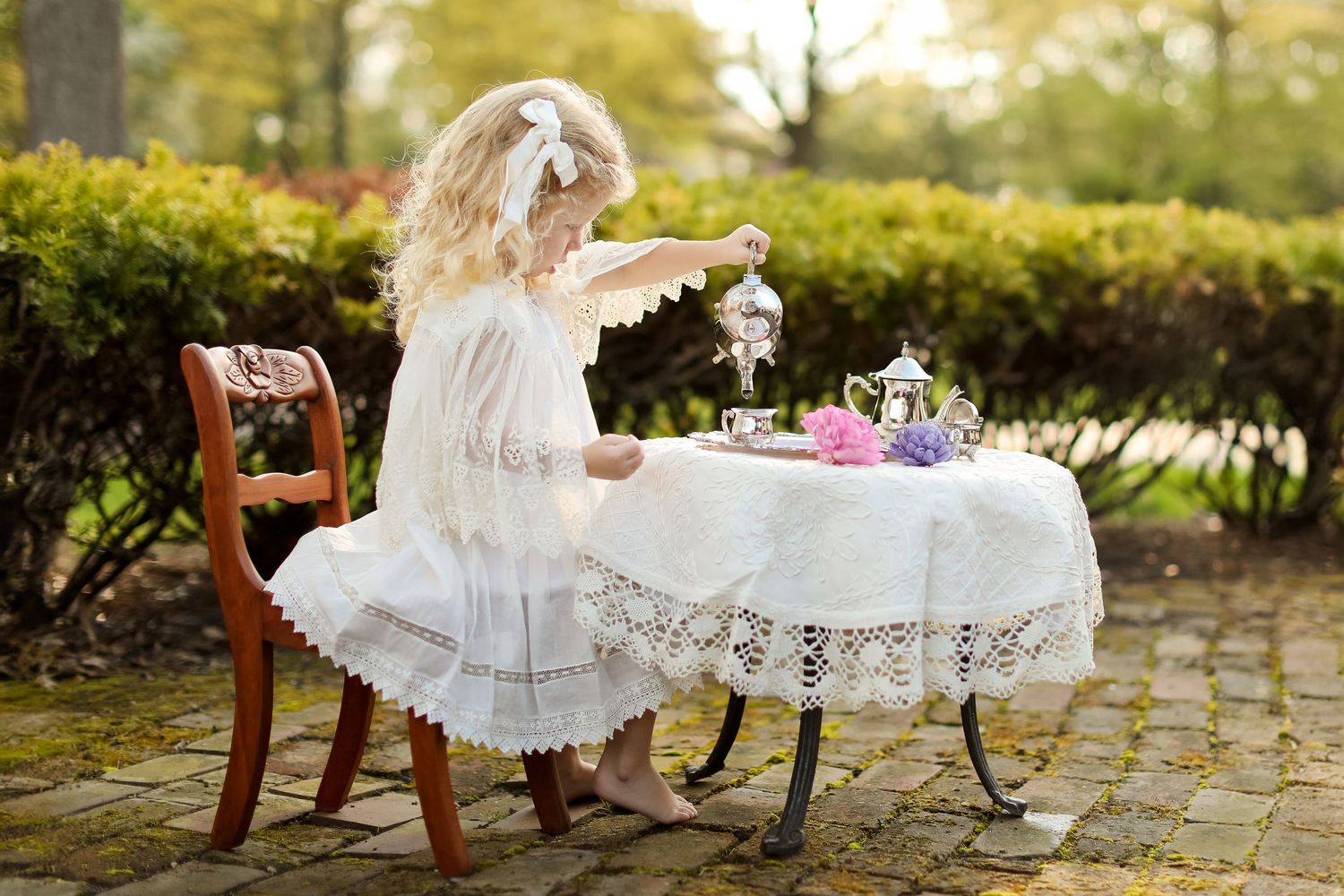 Vintage-inspired outdoor tea party setup with delicate lace details and garden furniture.