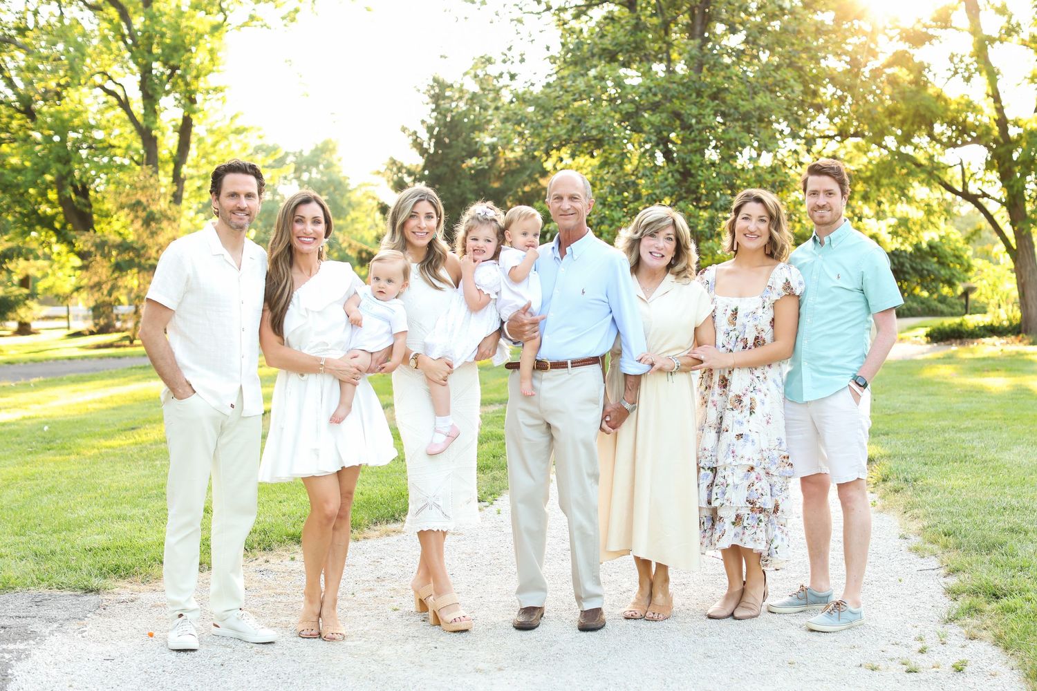 Extended family gathering in white and pastel outfits for outdoor summer photos.