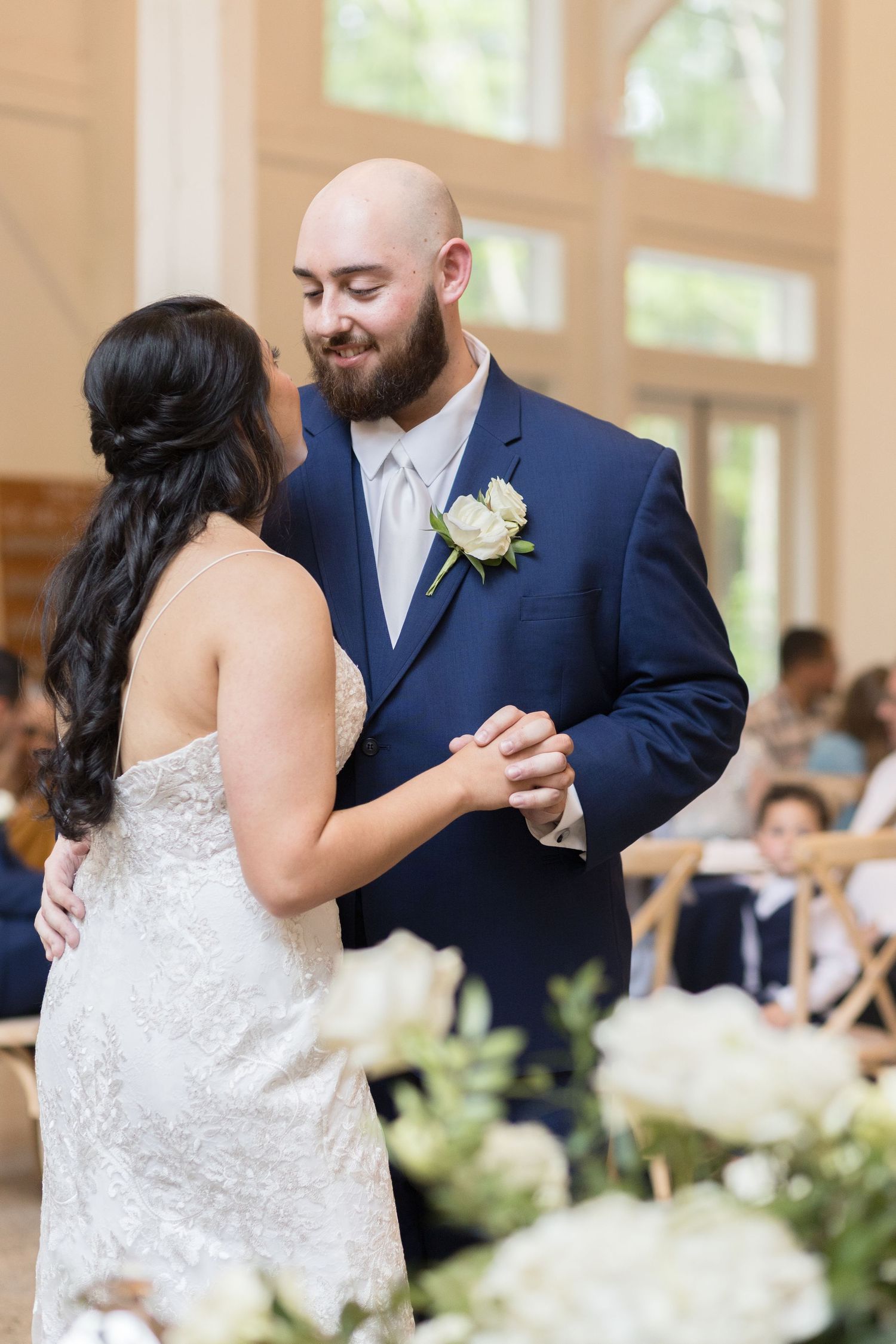 A couple shares a first dance at their reception, with white floral decorations visible in the foreground. Raleigh NC Wedding Photography