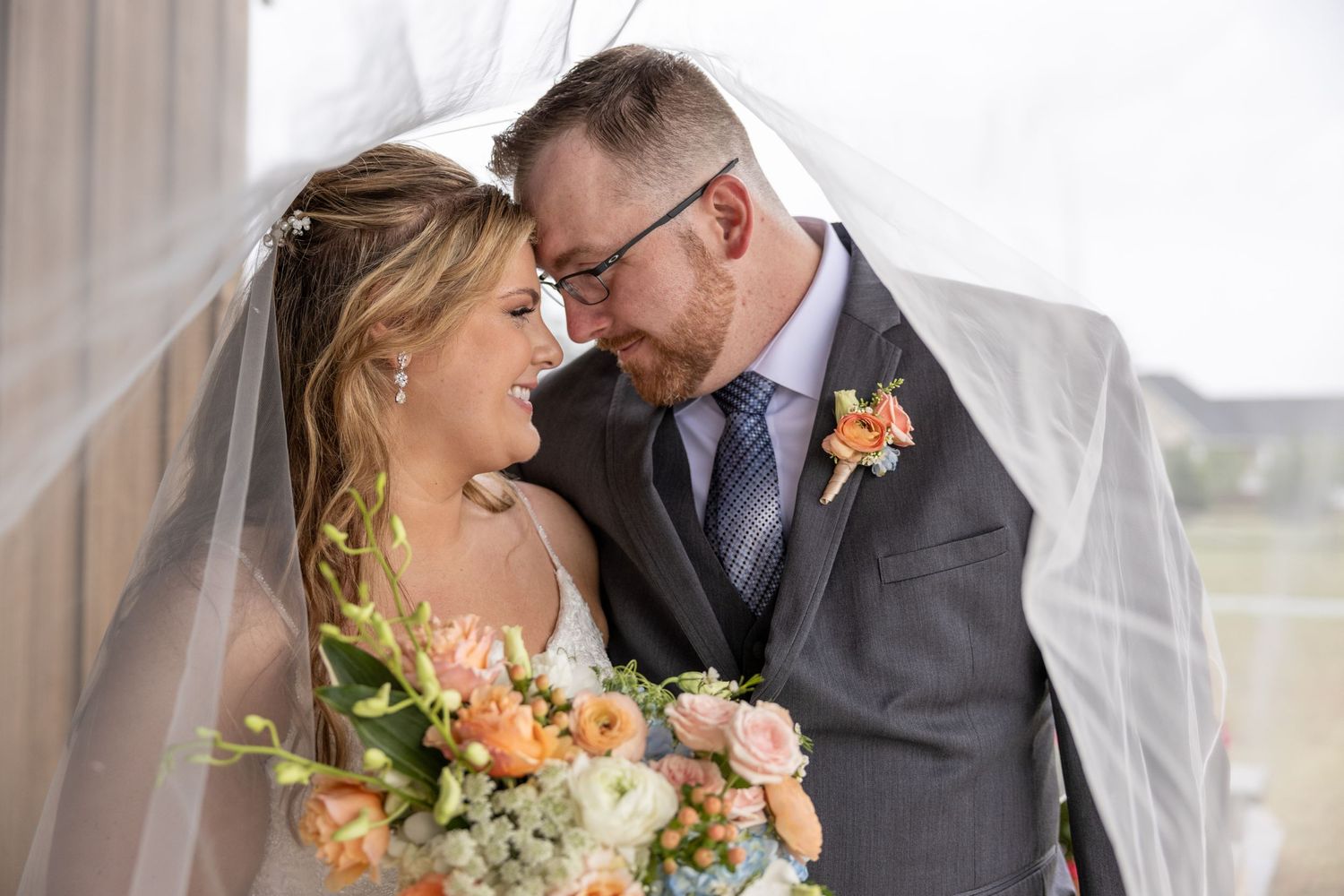 A couple under a veil after being married at Wilkins Barn in Coats, NC.