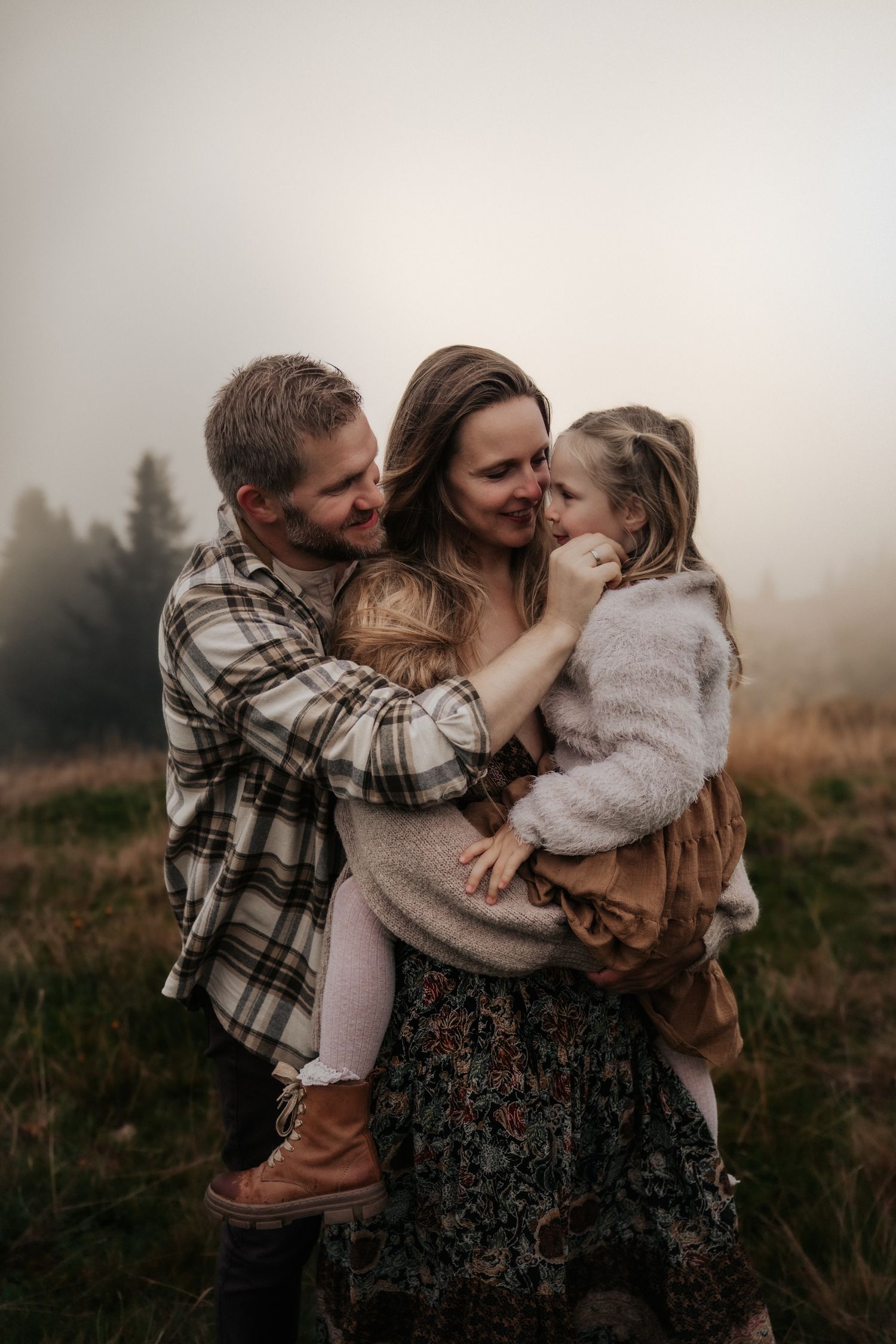 A family group poses together in warm sweaters by a mountain lake in autumn.