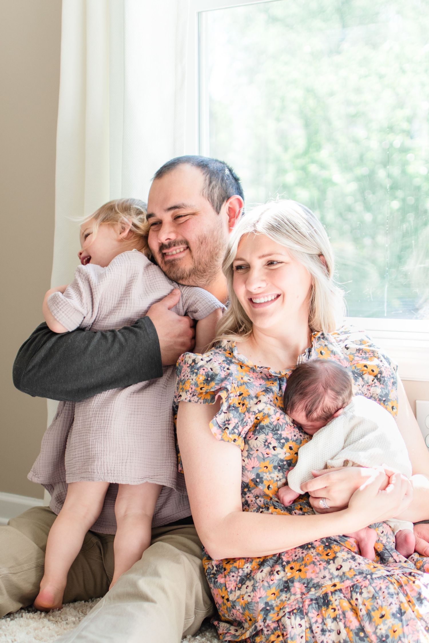 Dad gives big sister a hug as mom snuggles her newborn baby girl.