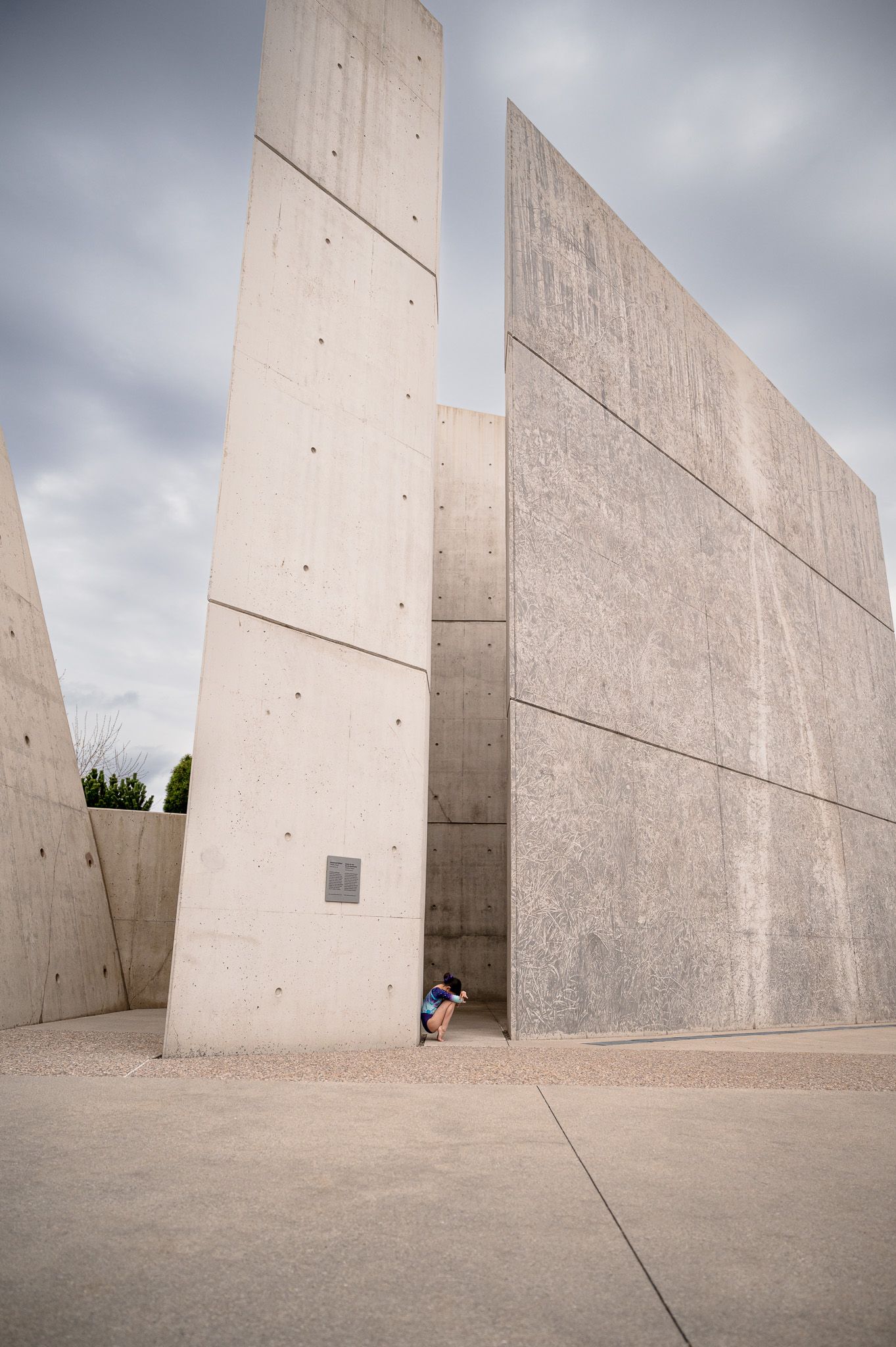 Small figure against towering concrete walls in modern architectural space.