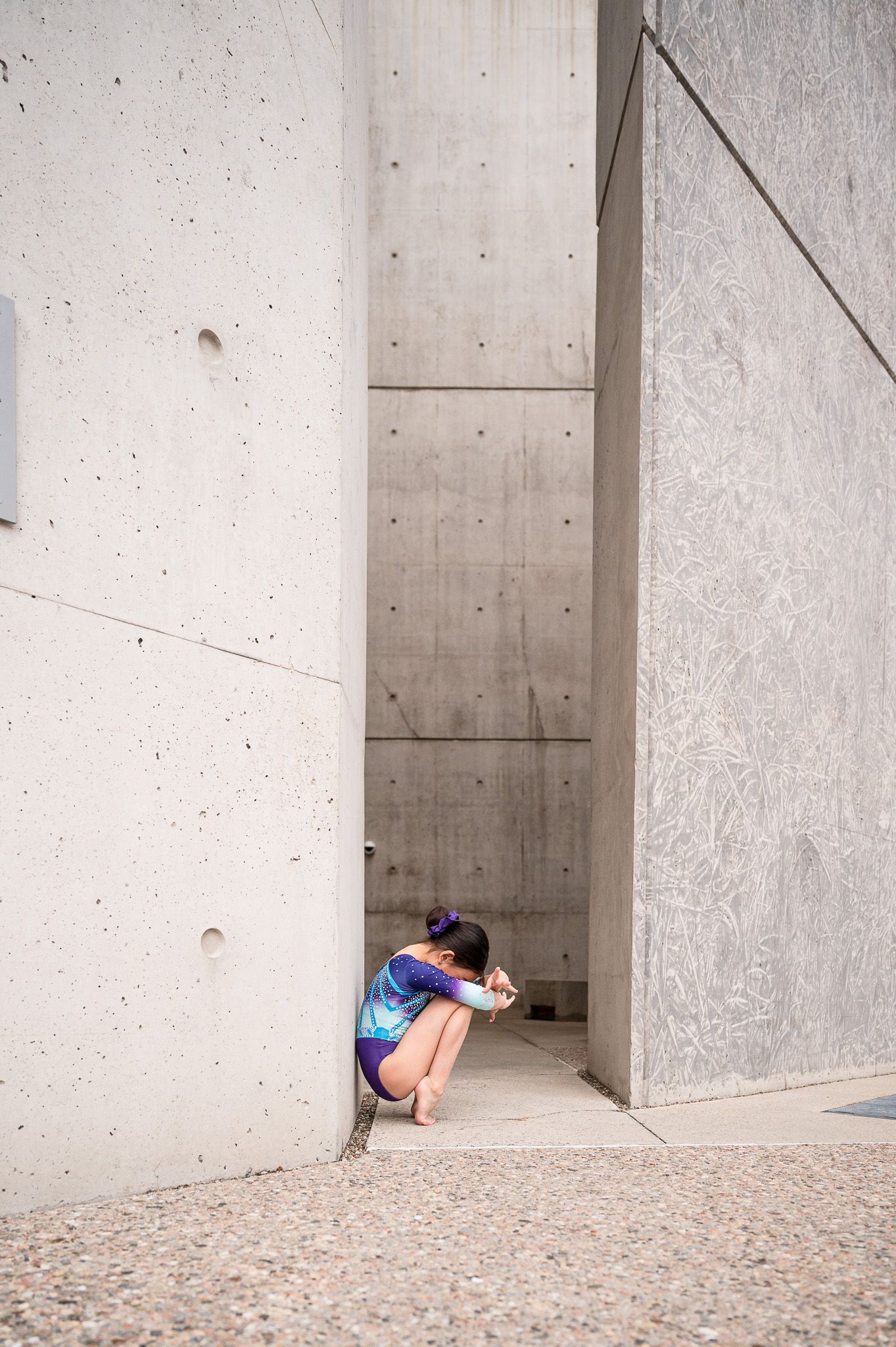 Person crouching in narrow concrete passageway.