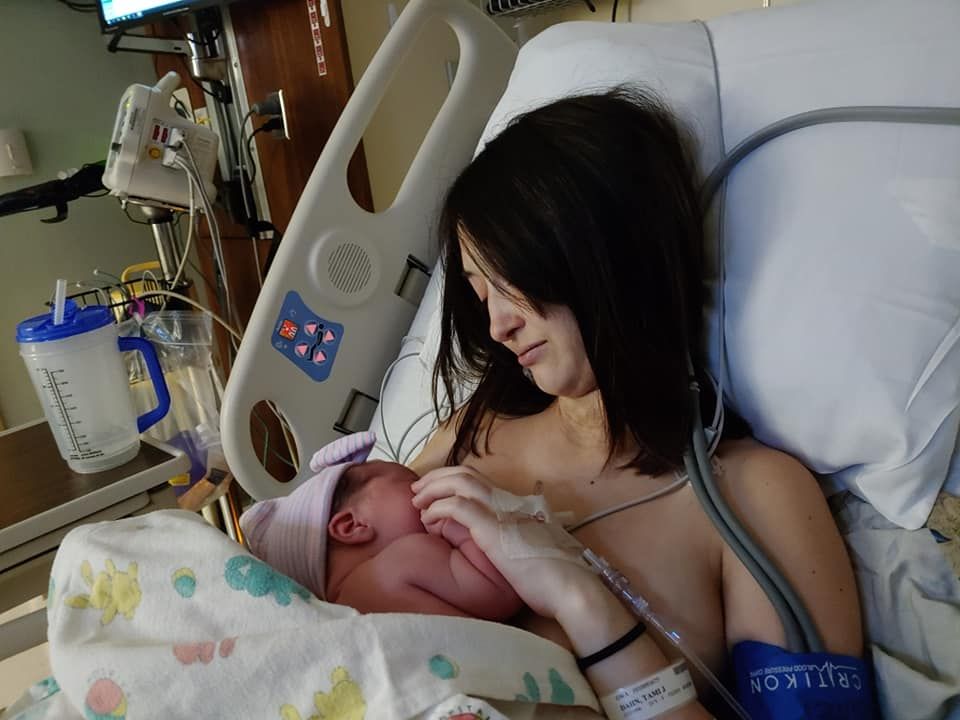Mother experiencing skin-to-skin contact with newborn baby in hospital bed.