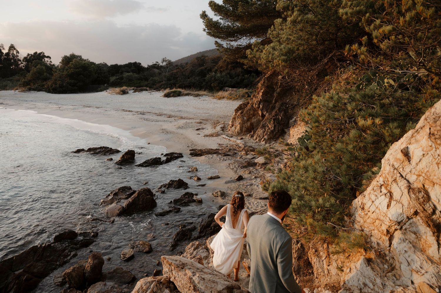 Two people share an emotional embrace at a wedding, with one wearing an intricate lace dress in a warmly lit setting.