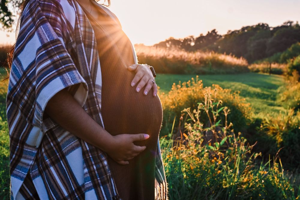 Young pregnant mother holding her belly at Prophetstown State Park in Lafayette, IN.