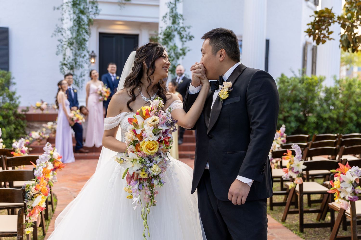 A wedding celebration at a beautiful courtyard venue with floral decorations and rustic wooden chairs.