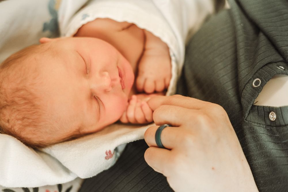 Newborn holding moms hand at the hospital