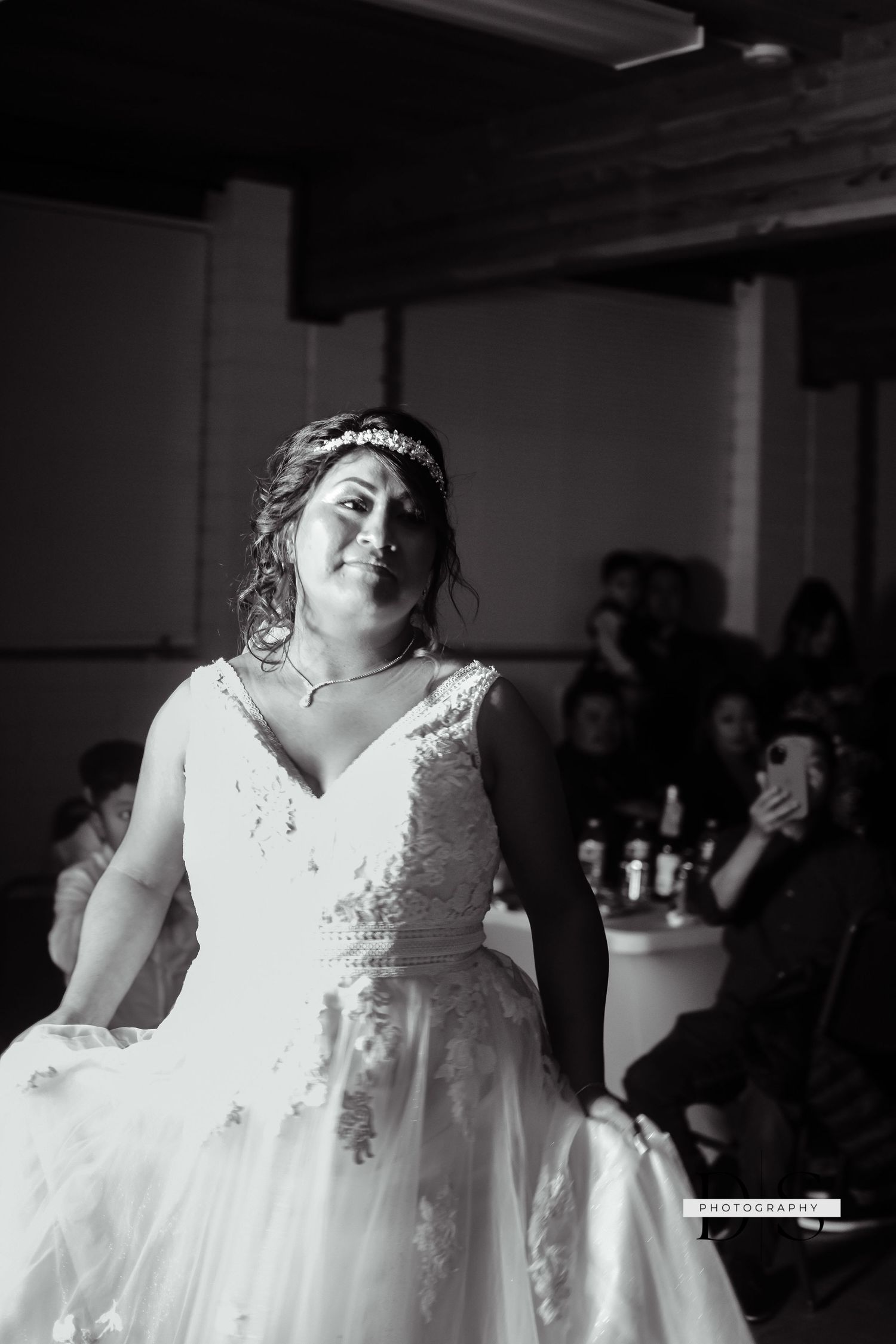 Black and white photograph of person in white wedding dress during reception.