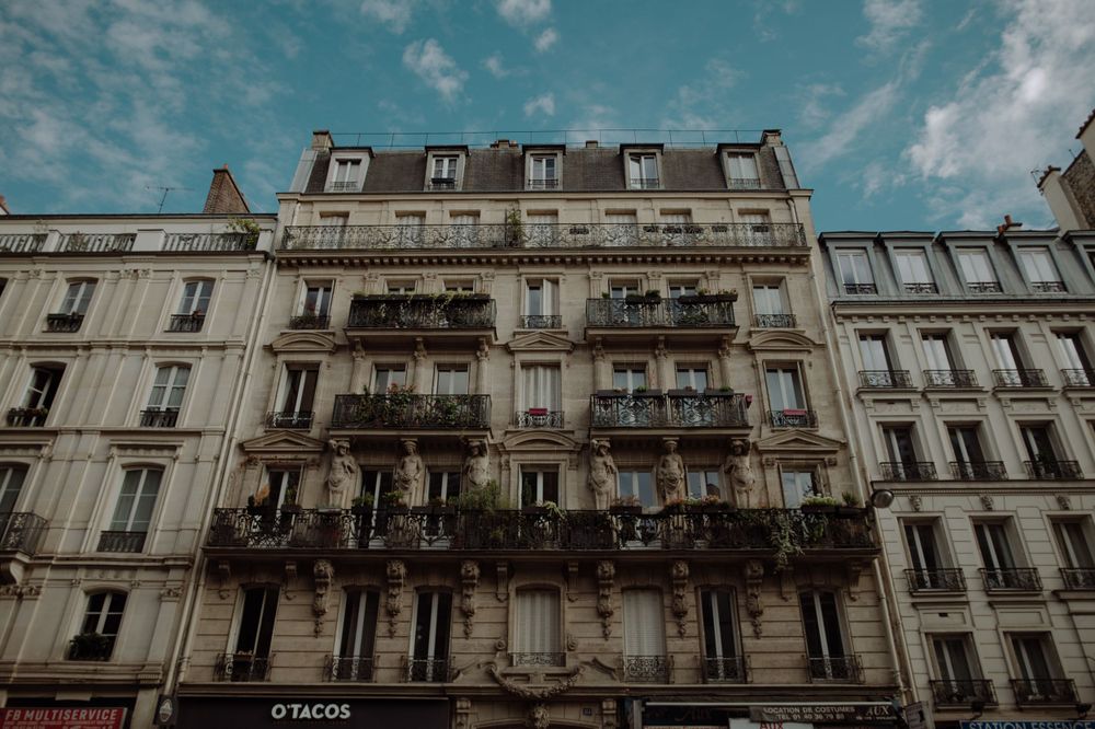 Classic Parisian apartment building with ornate balconies against a blue sky.