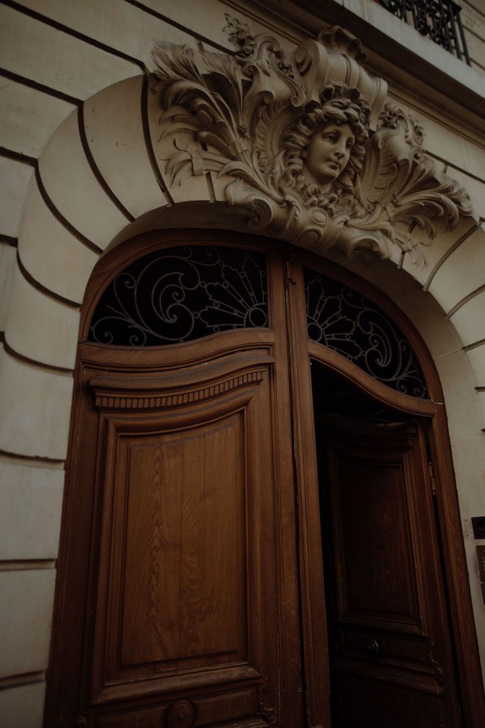 Ornate wooden doors with decorative carved stone archway and cherub details.
