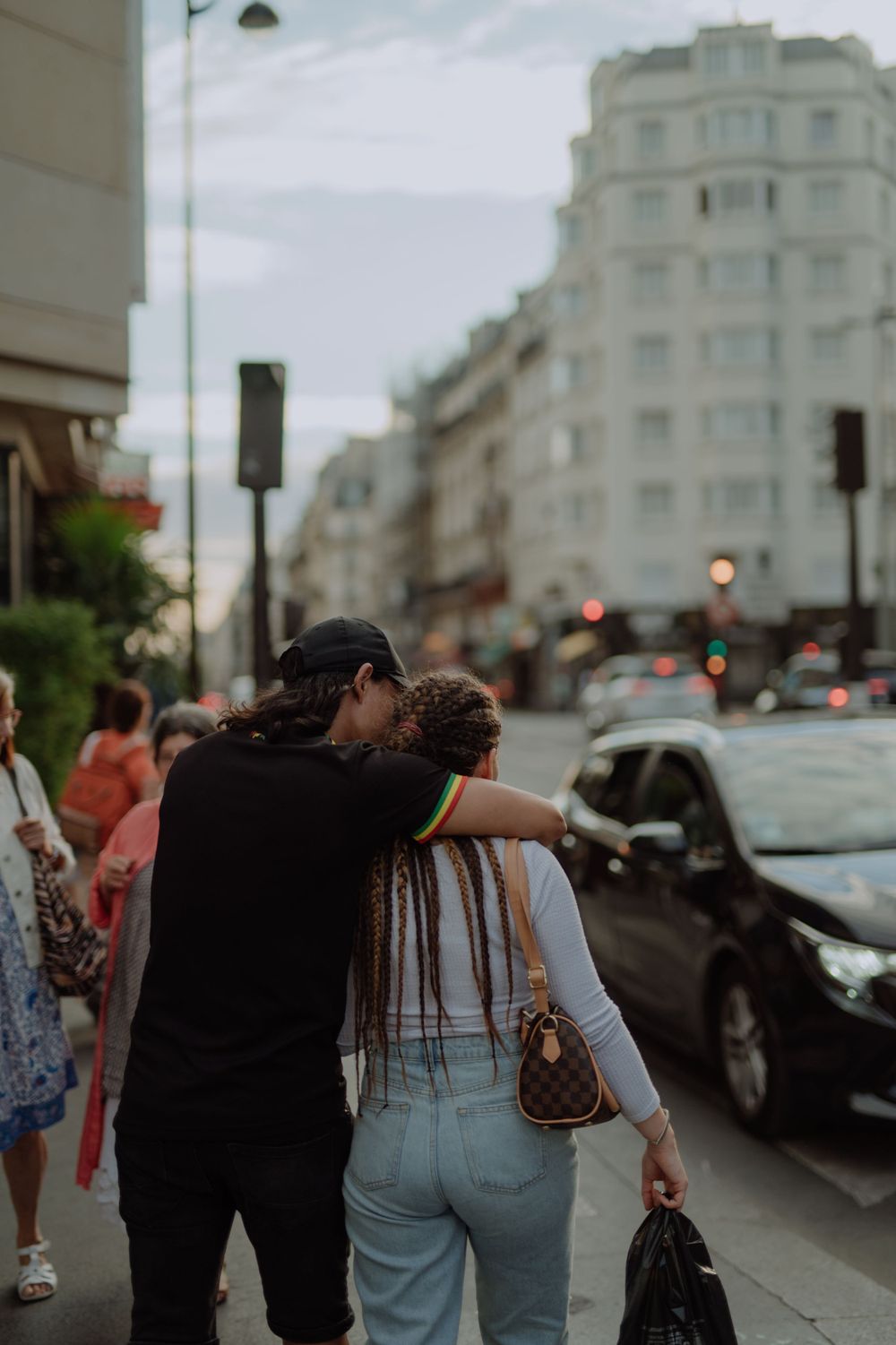 Intimate street scene of two people embracing on a rainy Parisian sidewalk.