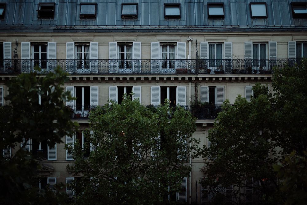Traditional Parisian apartment building facade with ornate balconies and mansard roof.