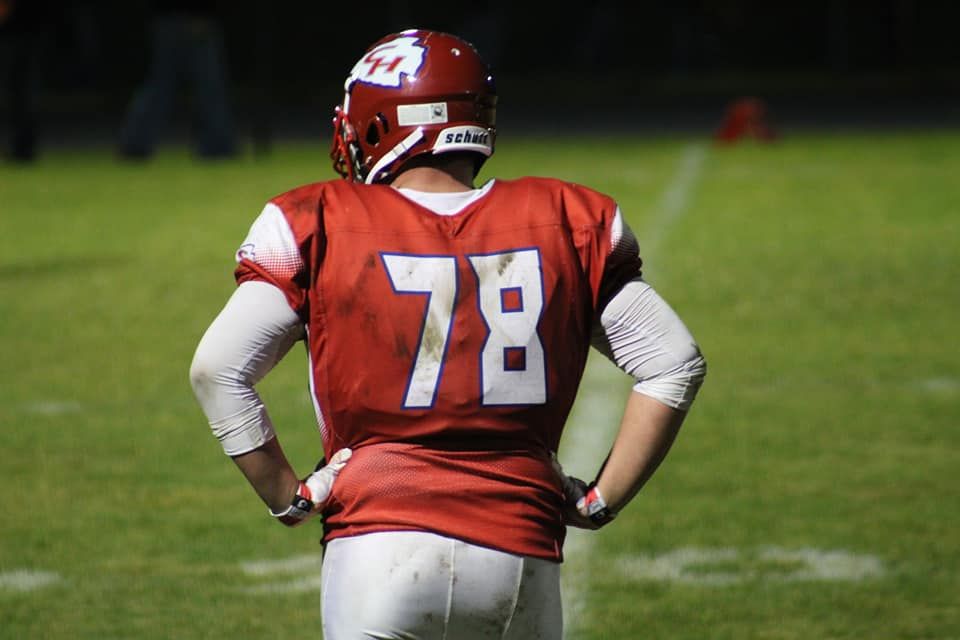 Football player wearing red jersey number 78 stands on field with hands on hips during a game.