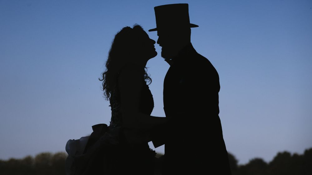 Silhouette of a romantic couple in formal attire against a blue twilight sky.

- BU Photography -