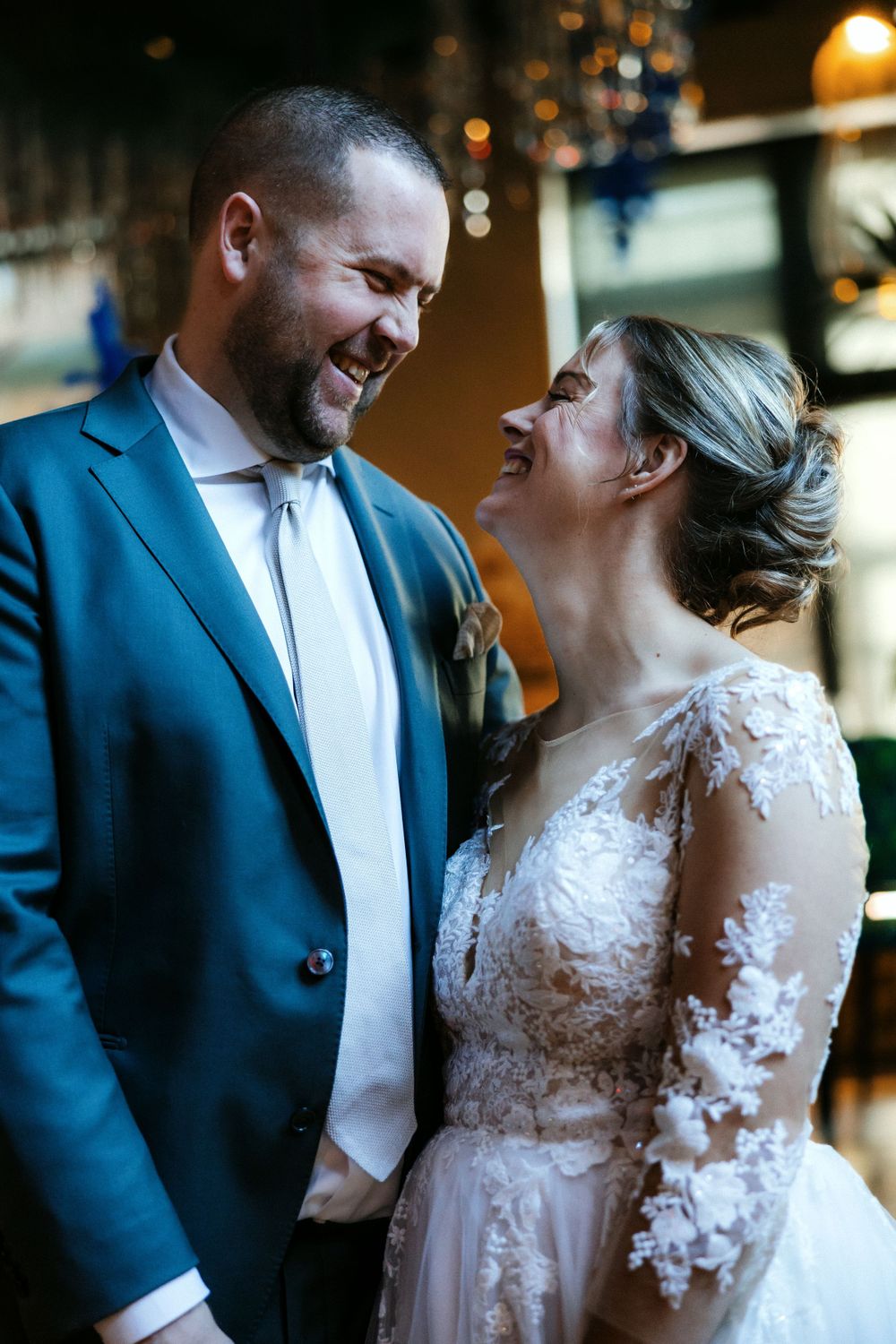 A joyful bride and groom share a candid laughing moment together at their wedding reception.