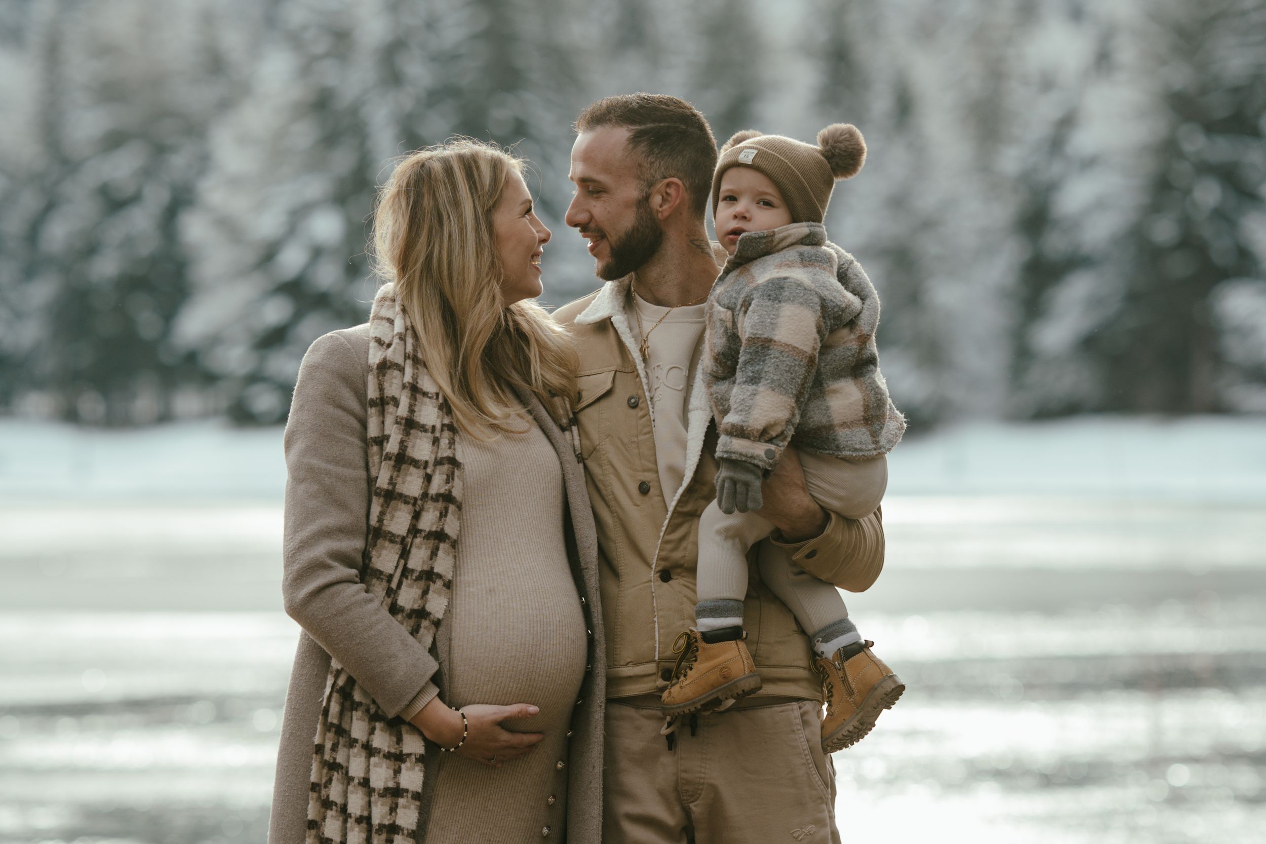 Family in warm winter clothing poses together in snowy mountain landscape.
