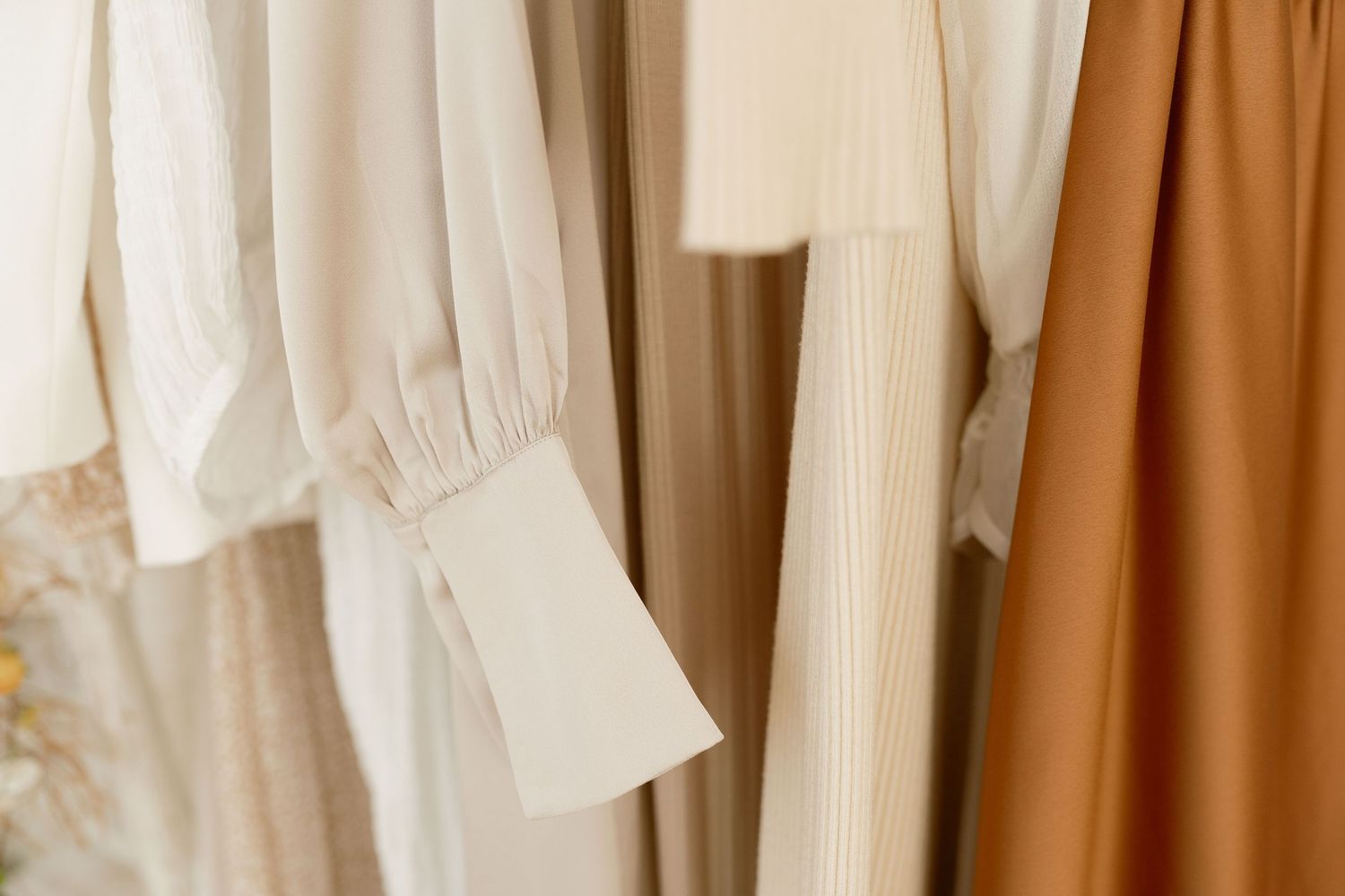 Neutral color palette of hanging garments in cream and caramel tones.