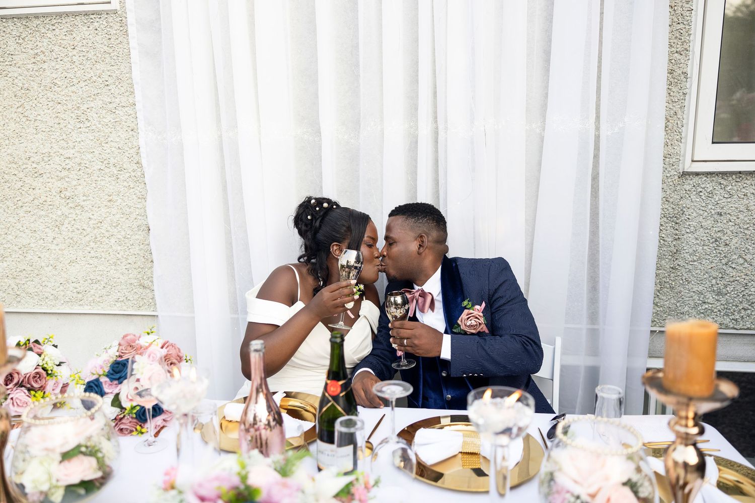 Newlyweds sharing an intimate moment at their reception table decorated with flowers.