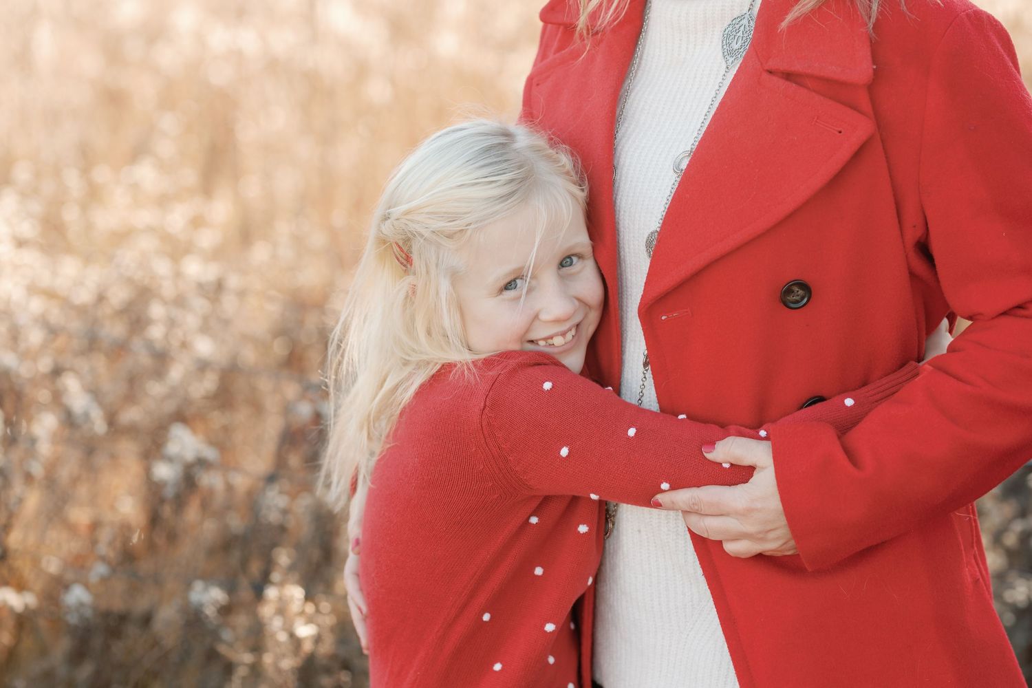 Couple in matching red coats embracing in a romantic outdoor photoshoot.