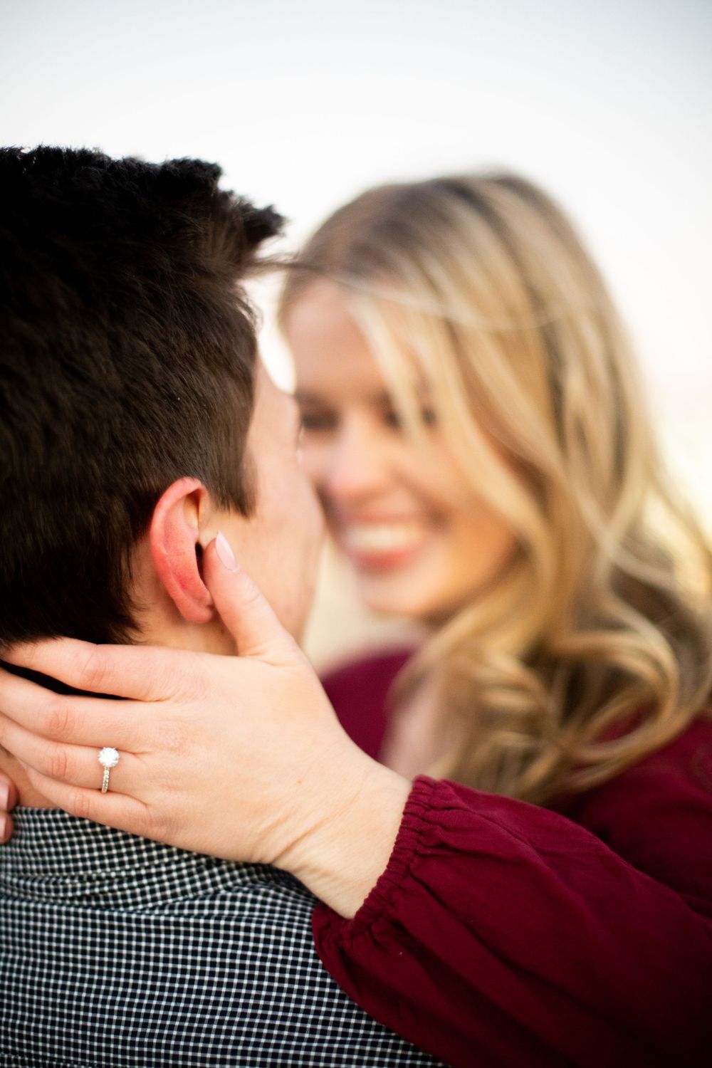 Close-up engagement photoshoot showing ring detail and intimate embrace.